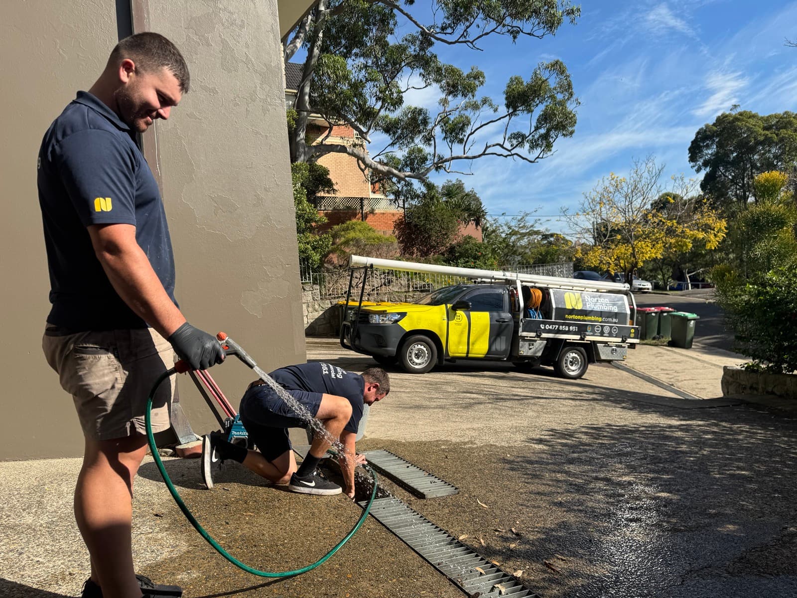 Adam and the Norton team jetting a blocked drain, branded truck in the background
