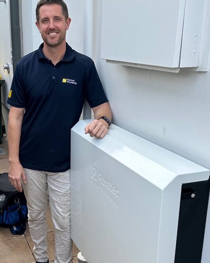 Adam from Norton Plumbing beside a finished Puretec FilterWall in Stone White at a Clovelly home
