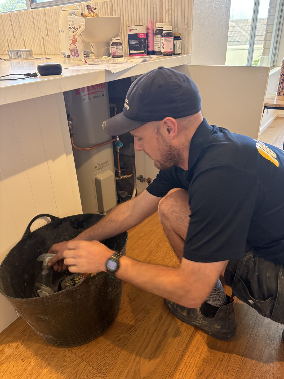 Adam Norton draining an Everhot electric storage hot water tank into a tub before replacing the temperature and pressure relief valve at a Coogee home