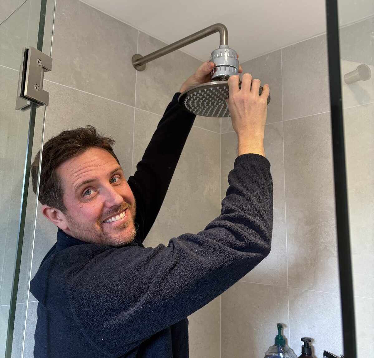 Adam Norton fitting a Puretec shower filter above a rain shower head in a Coogee bathroom
