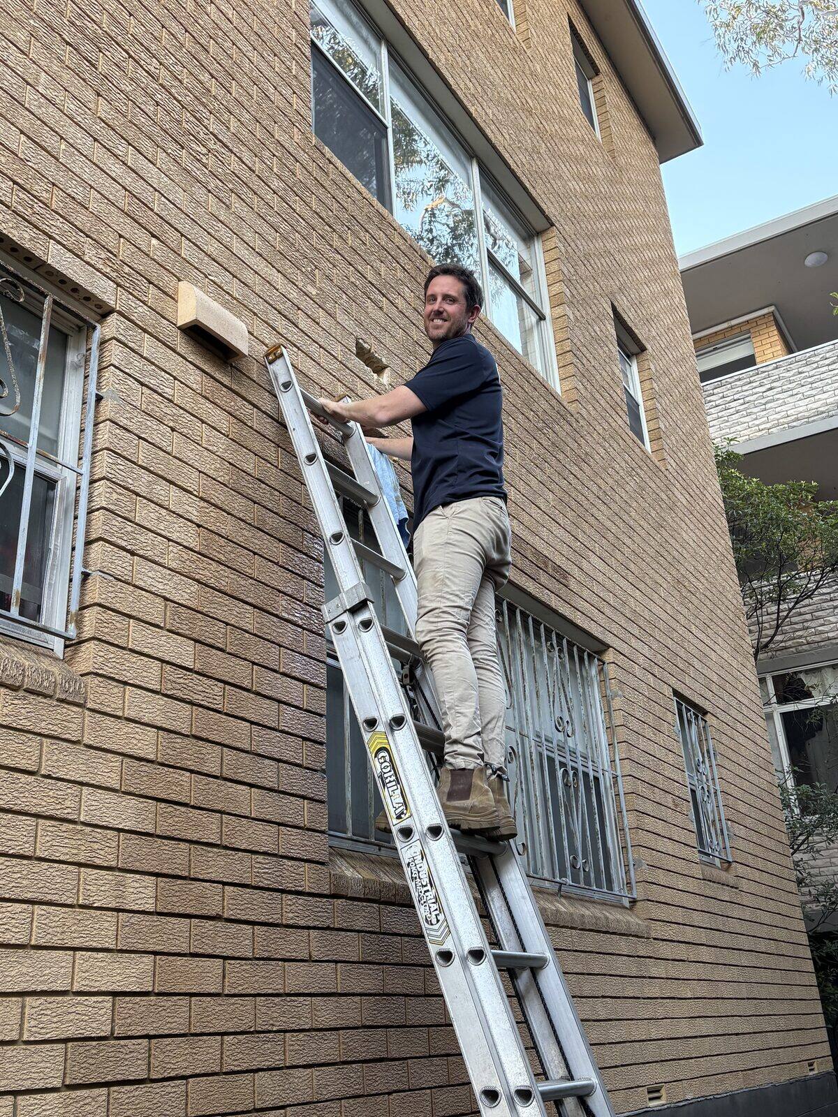 Adam Norton from Norton Plumbing reinstating face bricks on the external wall of a Coogee unit block after repairing a burst pipe inside the cavity