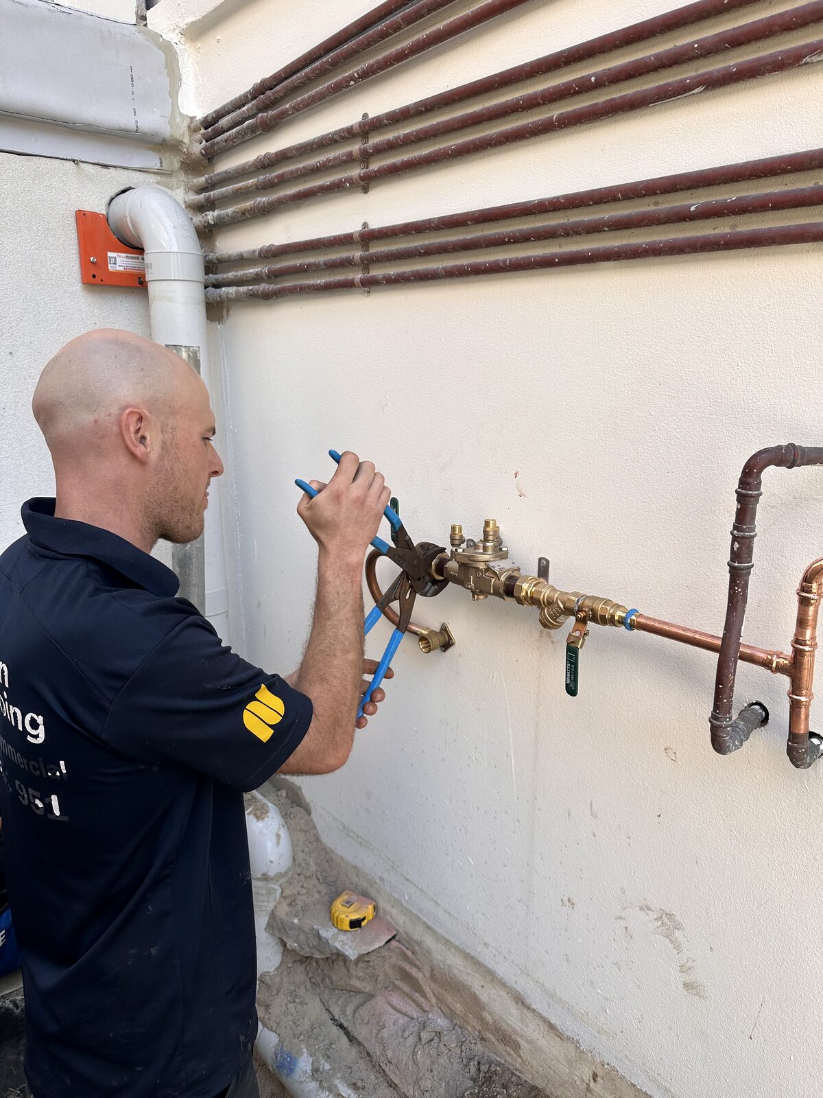 Adam Norton opening the isolation ball valve on a newly installed RPZ backflow prevention device at a Bondi property