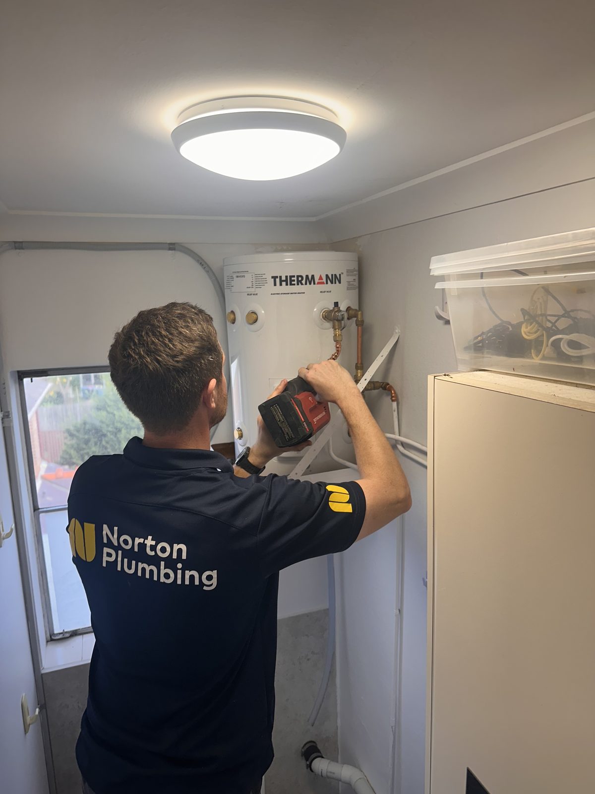 Adam Norton from Norton Plumbing installing a new Thermann electric storage hot water system at an Eastern Suburbs Sydney home