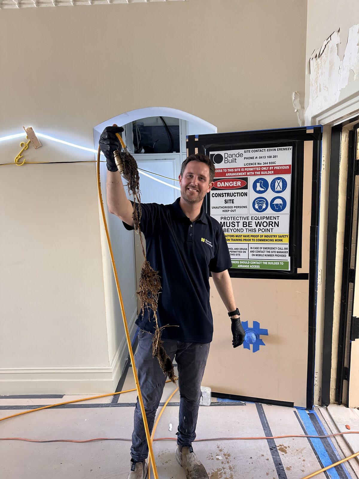 Adam Norton from Norton Plumbing holding a long mass of tree roots pulled from a blocked drain during a heritage home renovation in Point Piper