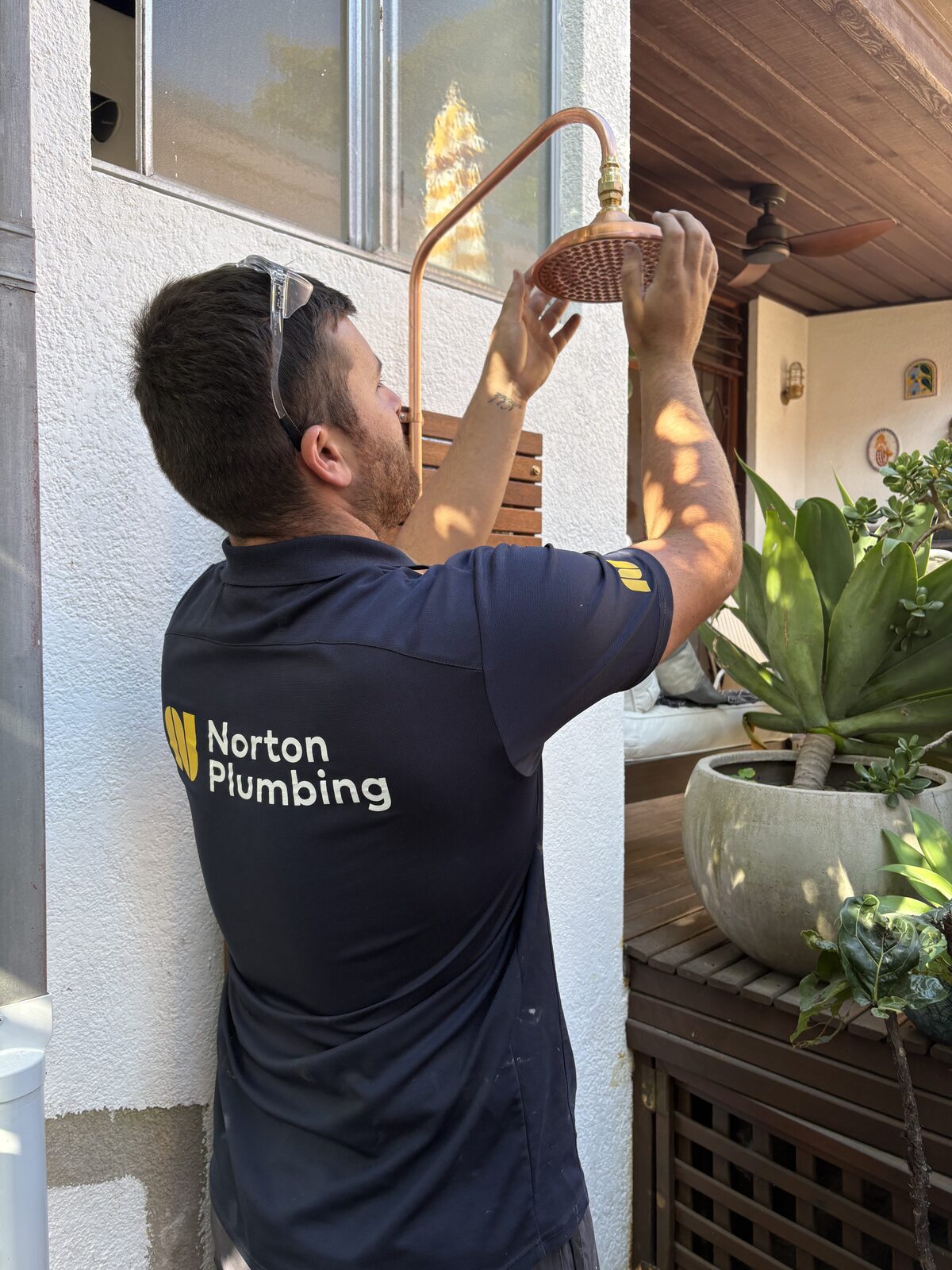 Blake from Norton Plumbing in a branded polo fitting the copper rose to the riser on the Mount Street outdoor shower in Coogee