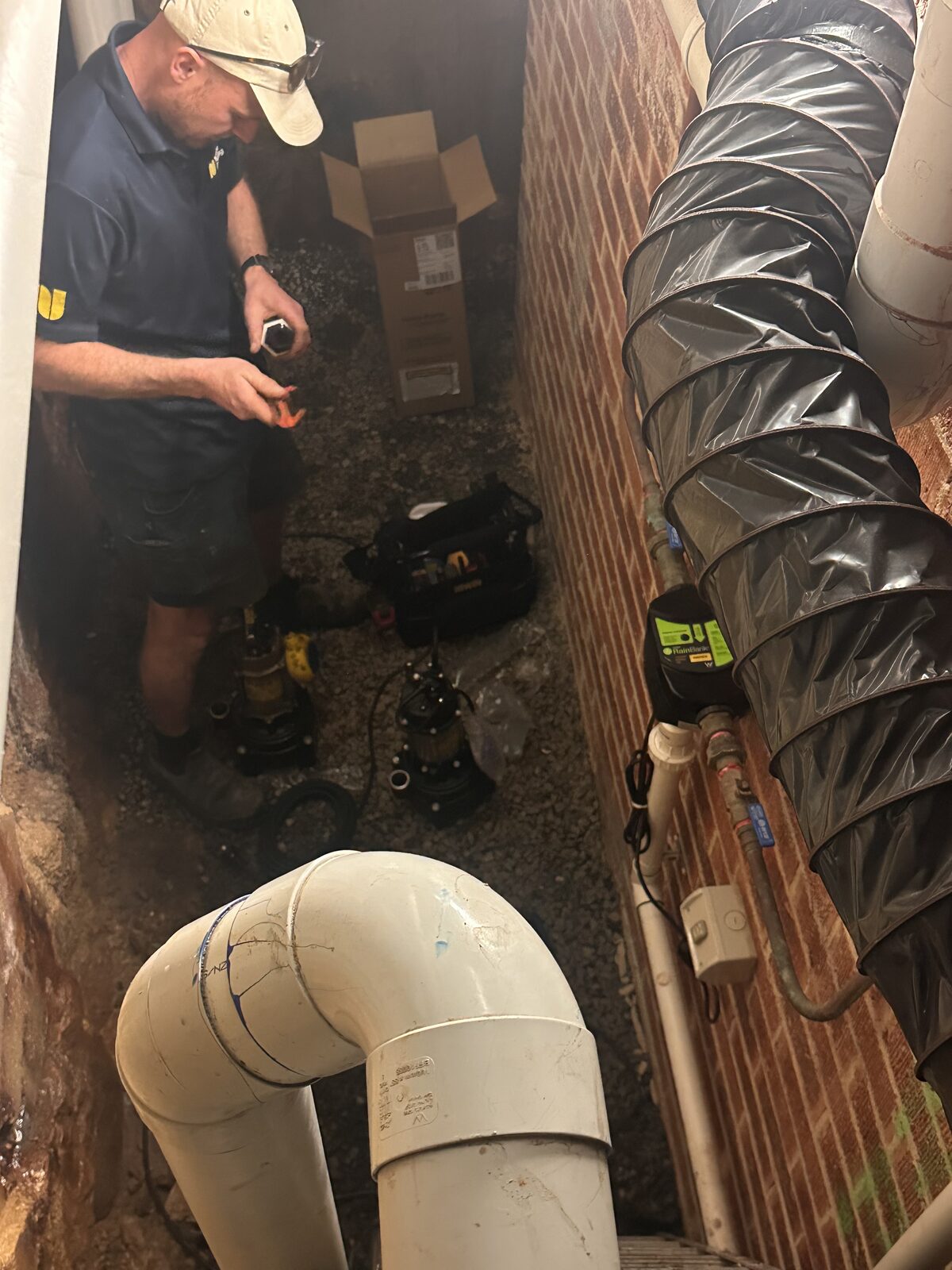 The old rainwater pump removed from a Dover Heights subfloor sitting on the gravel beside the new replacement submersible pump