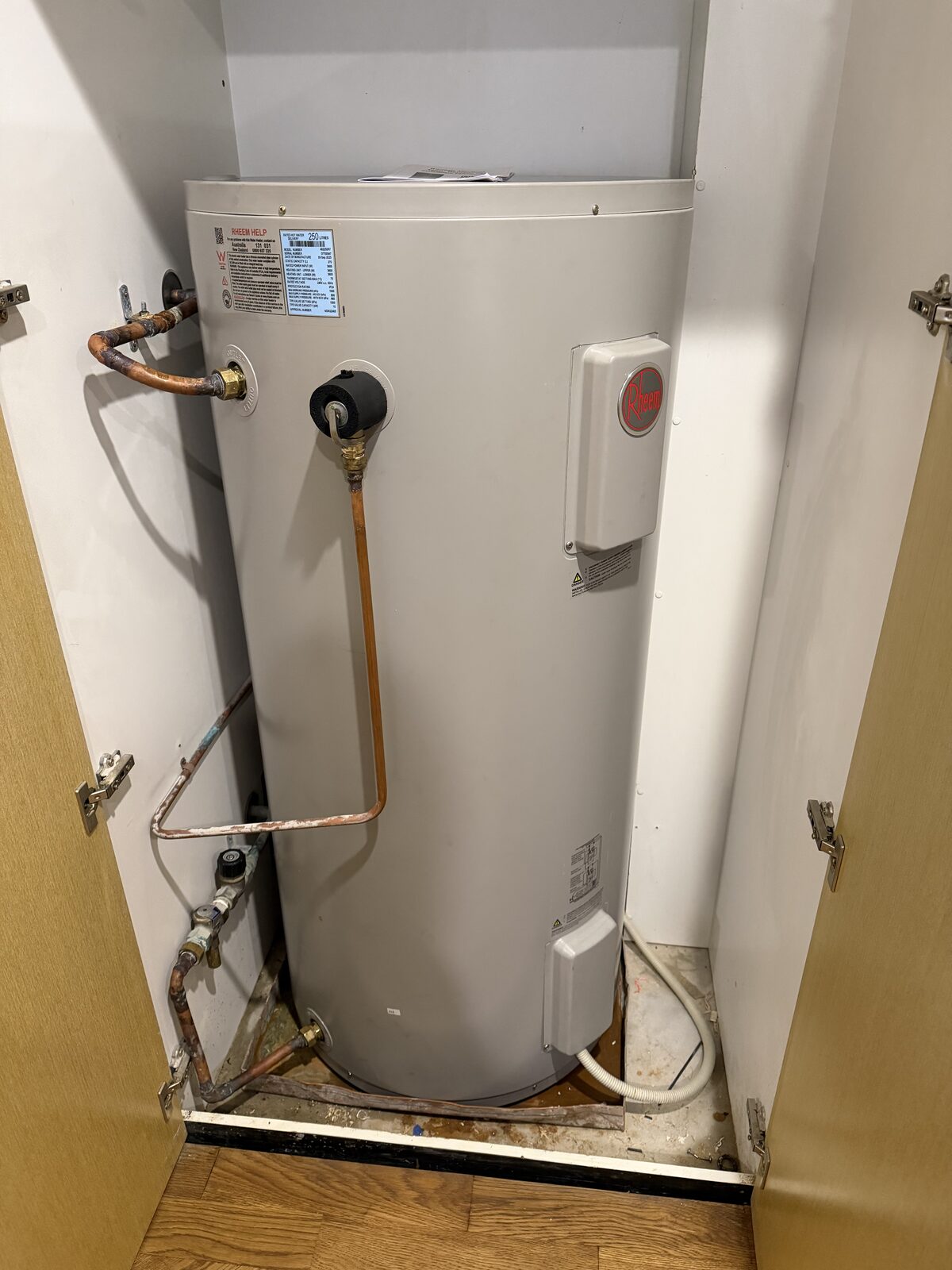 New Rheem 250 litre electric hot water system installed in a Darling Point apartment cupboard, with an insulated relief valve and copper drain line