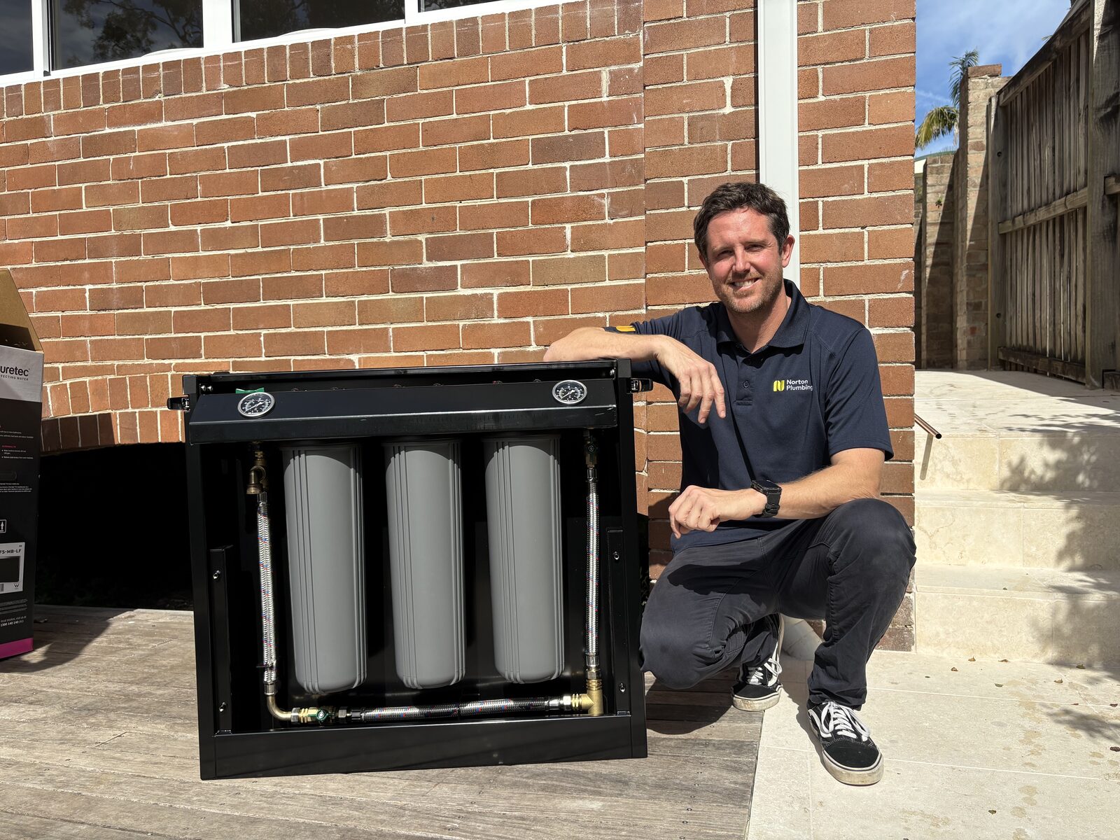 The Puretec FilterWall F Series opened to show the three filter cartridges and brass pipework inside the cabinet at a Randwick home