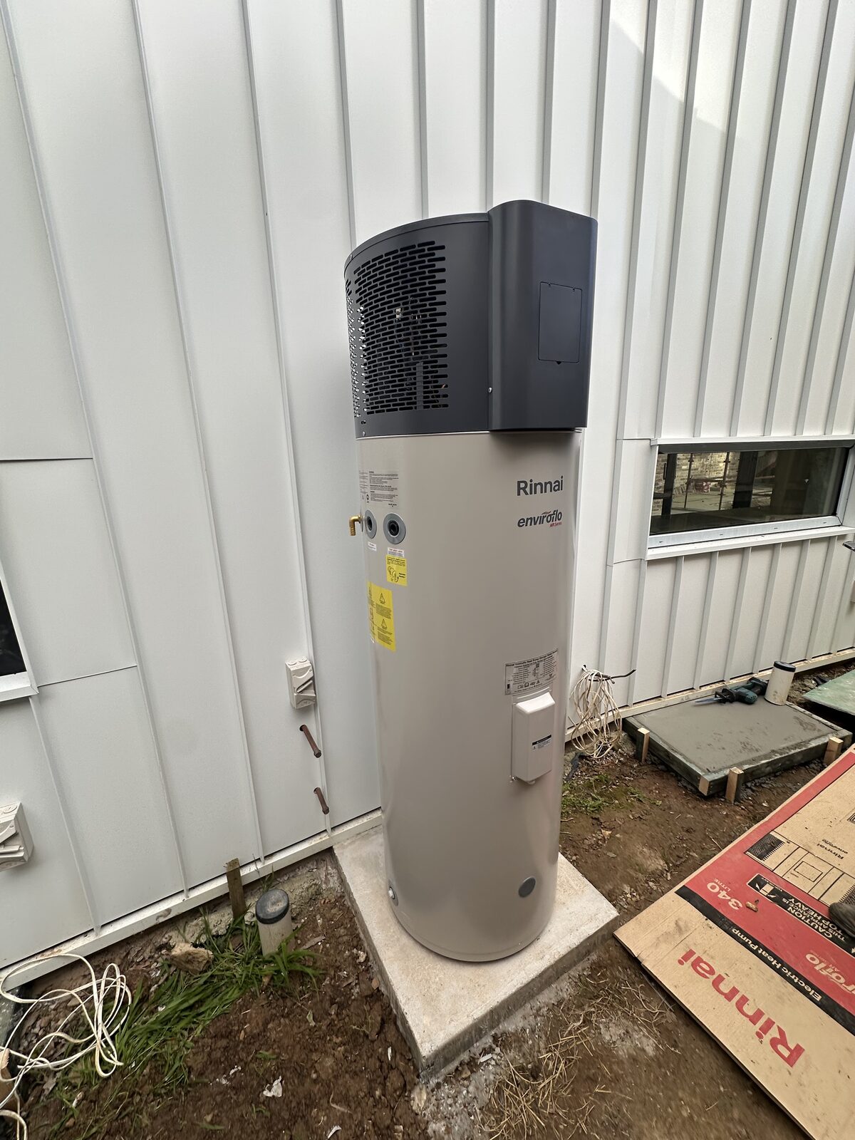 Completed Rinnai Enviroflo heat pump hot water system on a new concrete pad in Maroubra, showing lagged pipework, isolator and condensate drainage