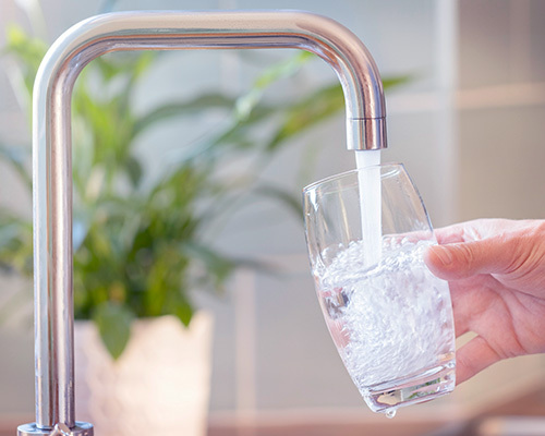 Clear glass of filtered water from a kitchen tap, representing reverse osmosis water purity